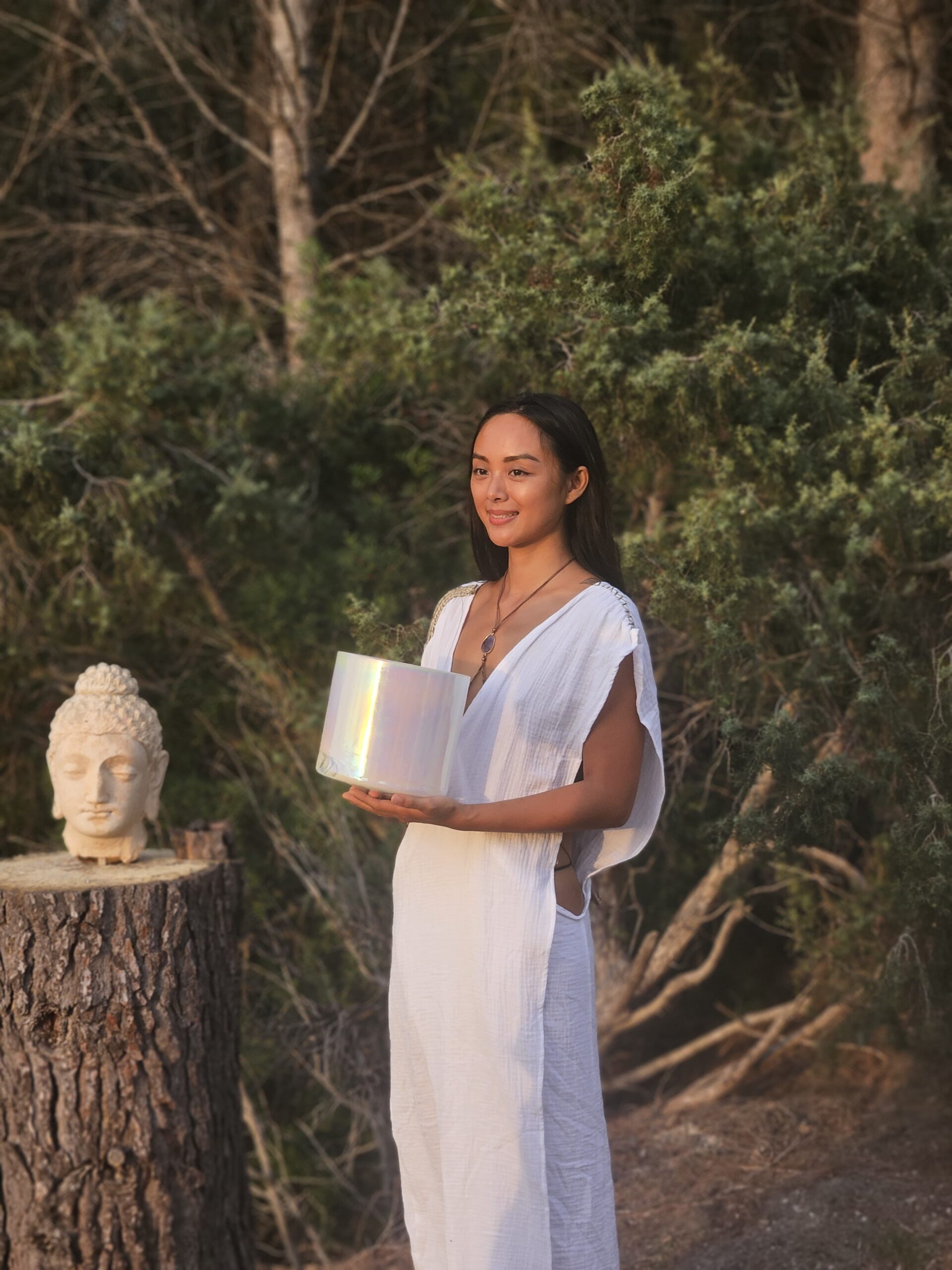 A woman performing a deep backbend yoga pose on a mat in front of a green moss wall at Miraclevie Sound Healing.