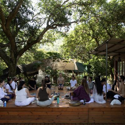 A group of people sitting in a circle for a sound healing and meditation retreat at Miraclevie Sound Healing in a lush forest setting.