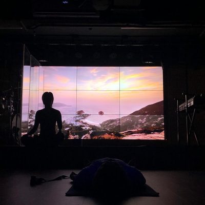 Yoga practitioner performing a standing balance pose against a city skyline and clear blue sky