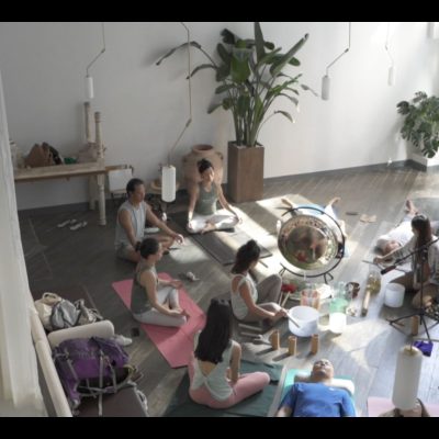 A woman playing crystal singing bowls for a sound bath session at Miraclevie Sound Healing.