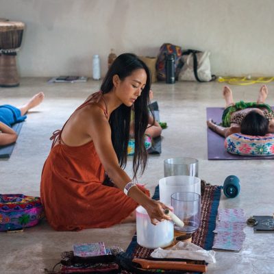 Miraclevie sound healing practitioner playing an iridescent crystal singing bowl by the sea waves.
