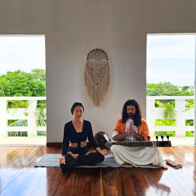 Overhead view of a Miraclevie sound healing practitioner leading a meditation session on a seaside terrace at sunset.